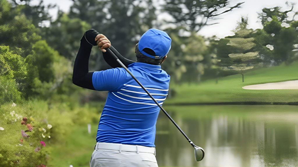 A man in a blue shirt and white pants is engaged in a golf game, focusing on his swing.