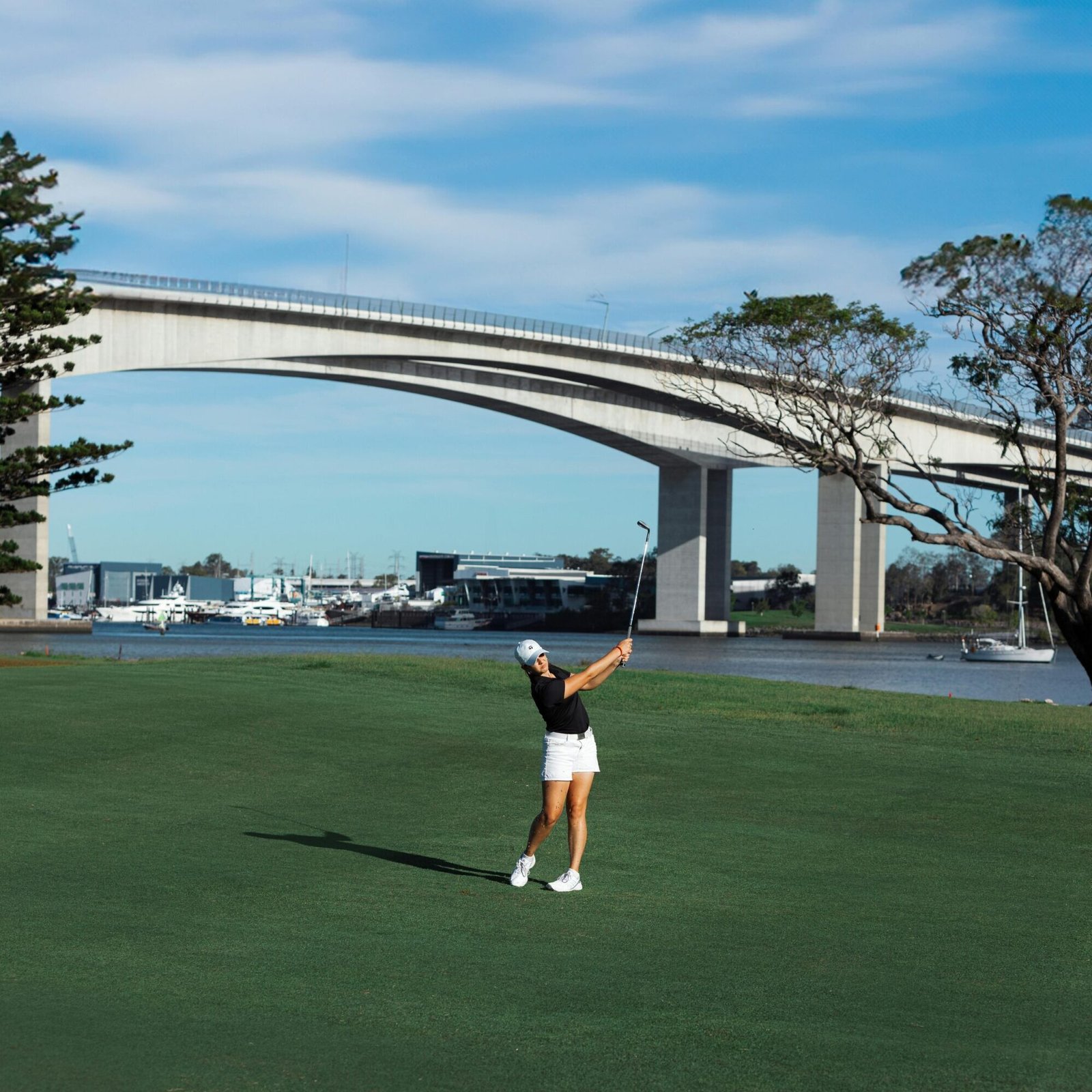 A Woman Playing Golf near the Gateway Bridge over Brisbane River